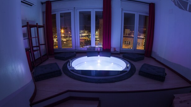 A circular hot tub with a view of the city at night. - Guesthouse 4Roomz (Bologna)