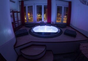 A circular hot tub with a view of the city at night. - Guesthouse 4Roomz (Bologna)