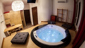 A room with a hot tub, wooden furniture, and a TV mounted on the wall. - Guesthouse 4Roomz (Bologna)