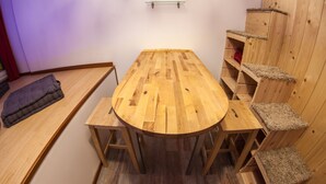 A wooden dining table with benches, a small shelf unit, and a pet bed. - Guesthouse 4Roomz (Bologna)
