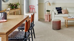 A modern living room with a sofa, a coffee table, and a dining area with a table and chairs.