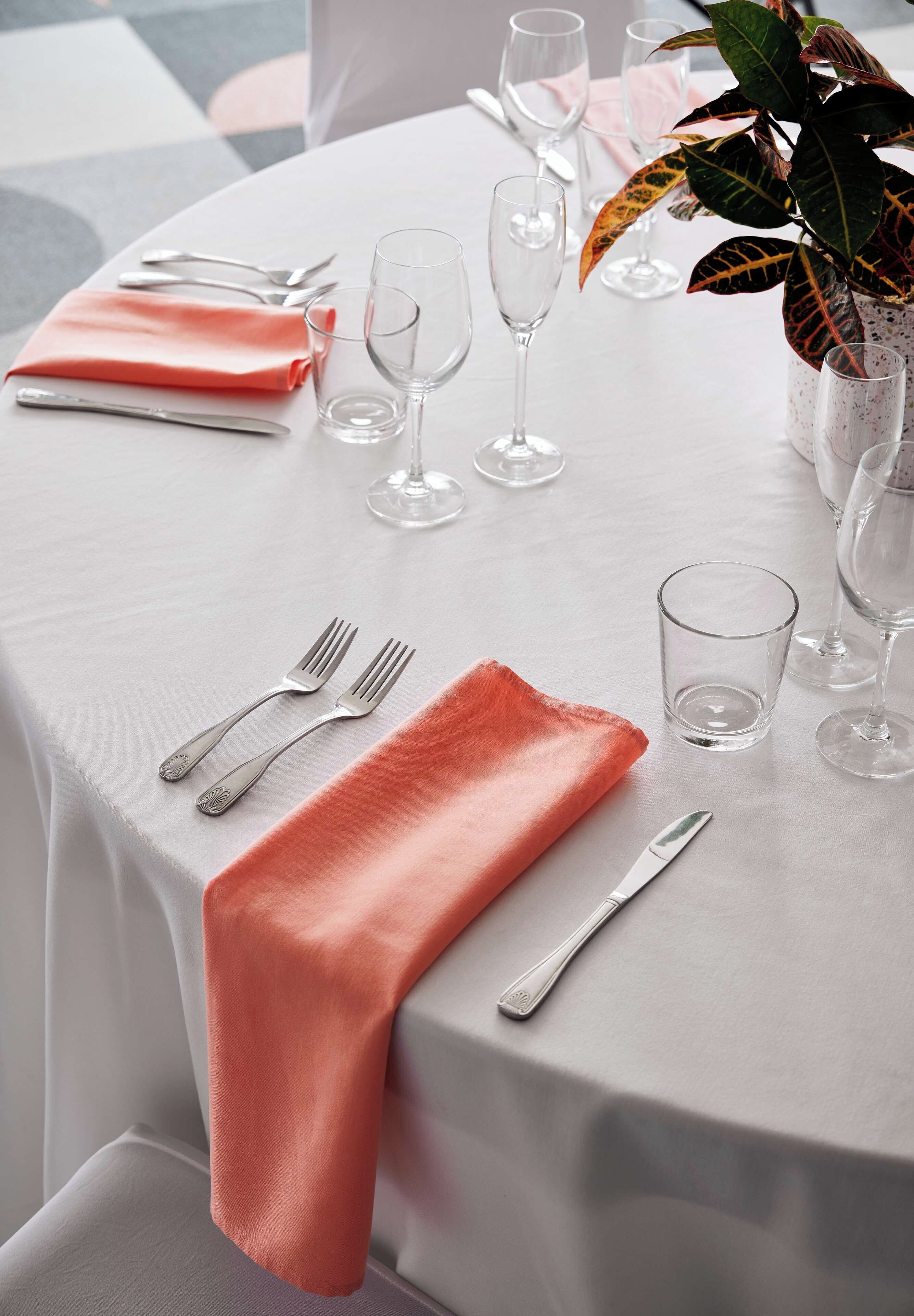 A table set for dining with a white tablecloth, silverware, and clear glassware.