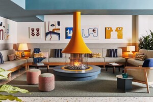Una sala de estar moderna con chimenea de vidrio en el centro, sofás a rayas y arte abstracto en las paredes.