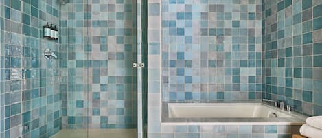 A bathroom with a glass-enclosed shower, a bathtub, and a tiled wall.