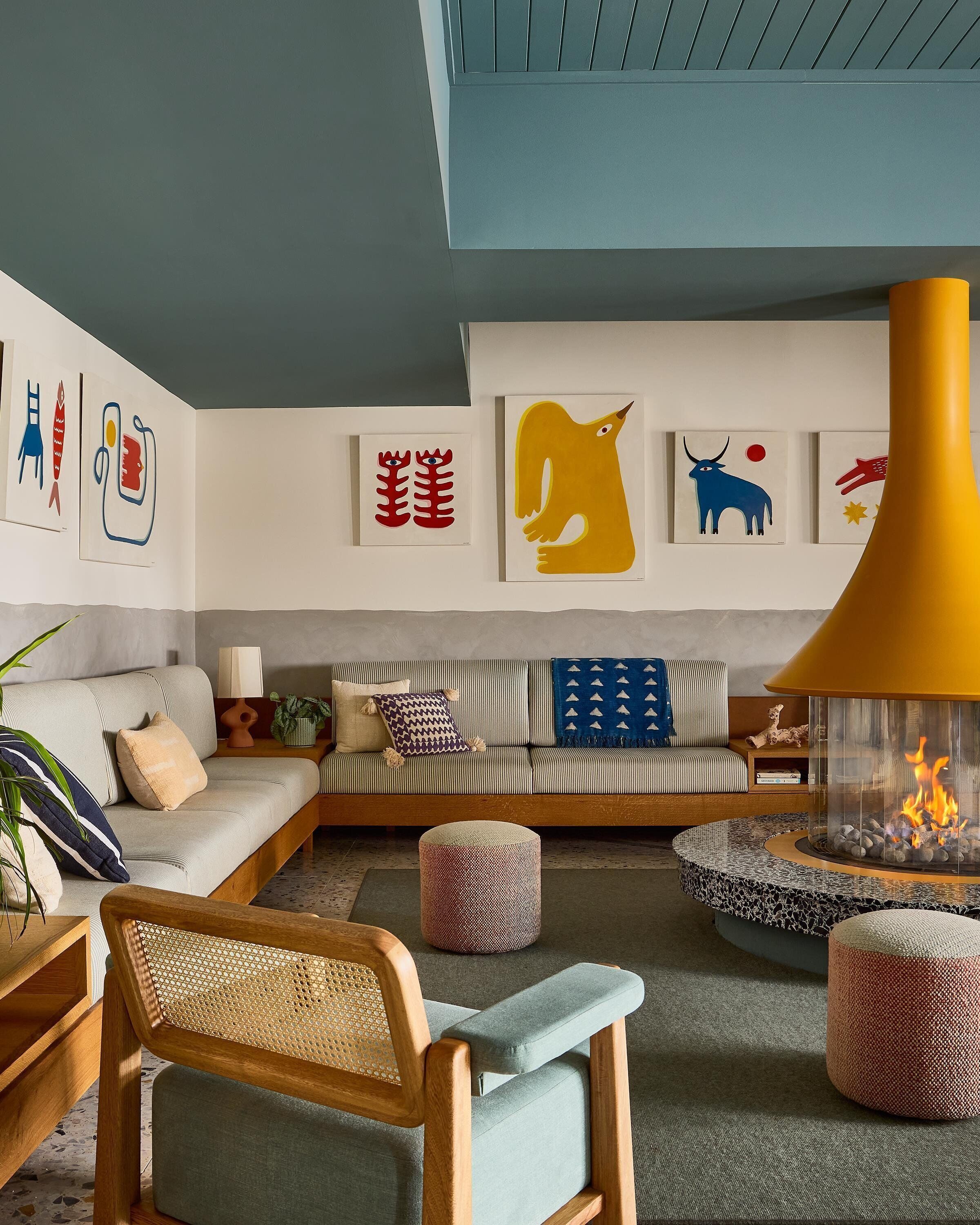 Una sala de estar moderna con un sofá, un sillón, una chimenea y arte abstracto en la pared.