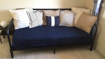 Um sofá azul escuro com várias almofadas em um quarto com piso de madeira clara.