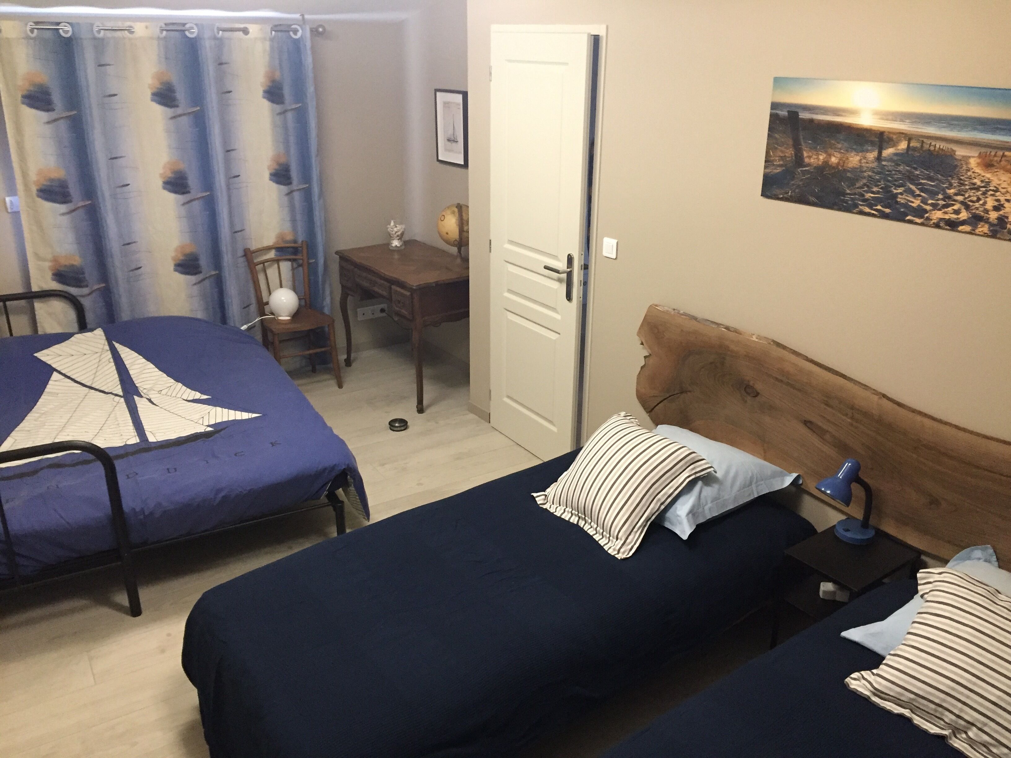 Un dormitorio con dos camas, un escritorio, una silla y un cuadro en la pared.
