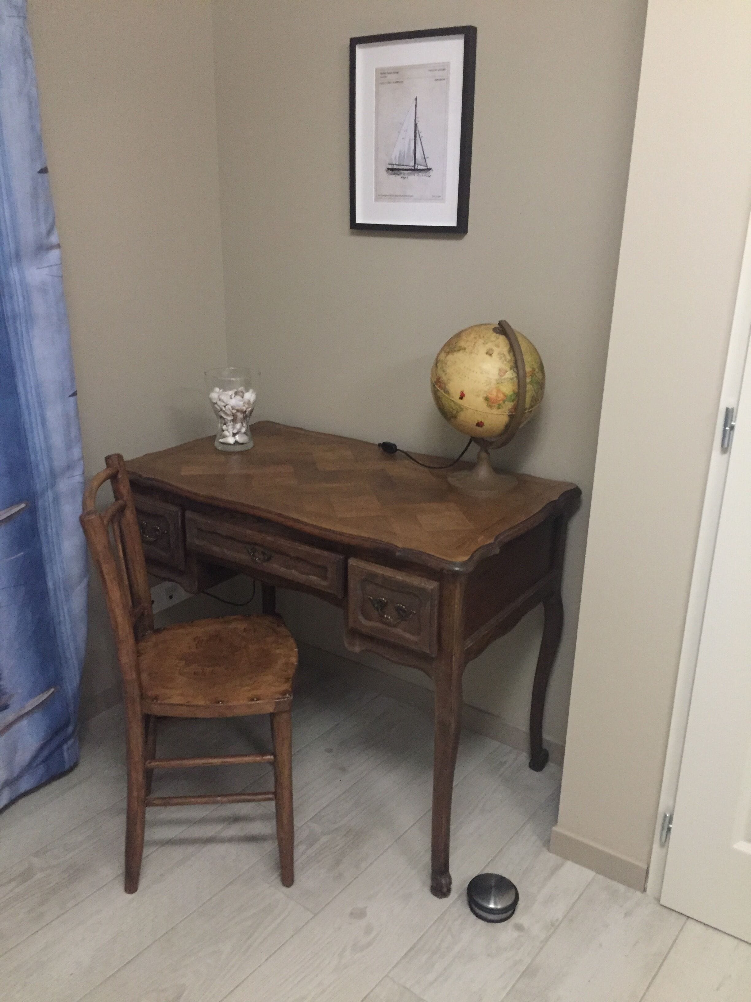 A wooden desk with a globe and a framed picture on the wall.