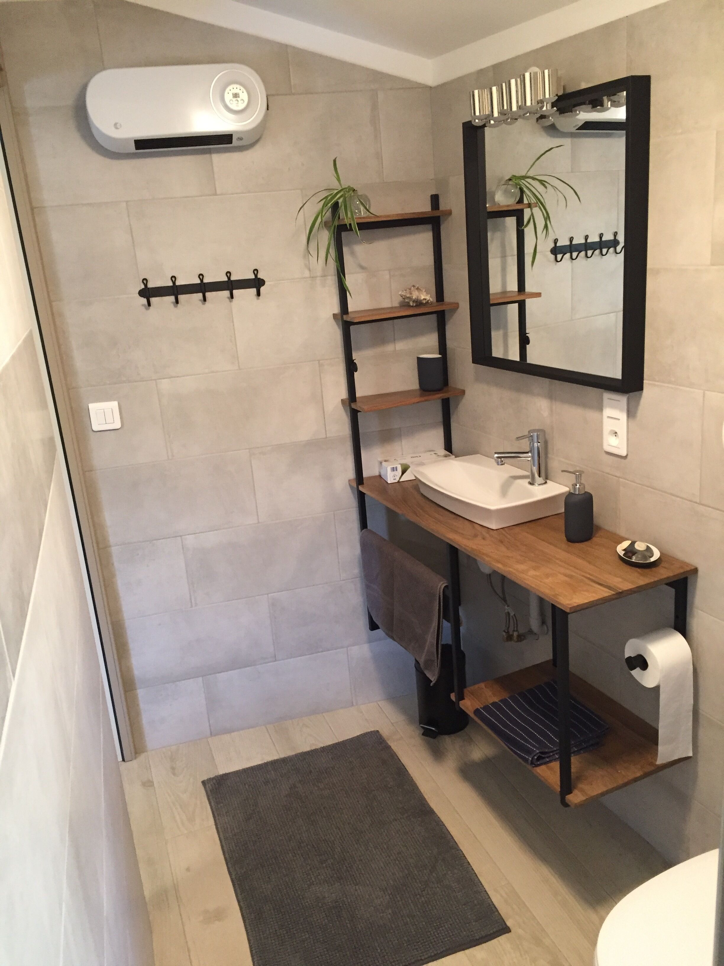 A modern bathroom with a wooden vanity, a white sink, a mirror, and a towel rack.