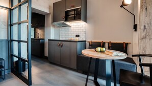 A modern kitchen with dark cabinetry, a built-in oven, and a round table with a bowl of fruit and a book. - CLOUD No7 LOFTS (Stuttgart)