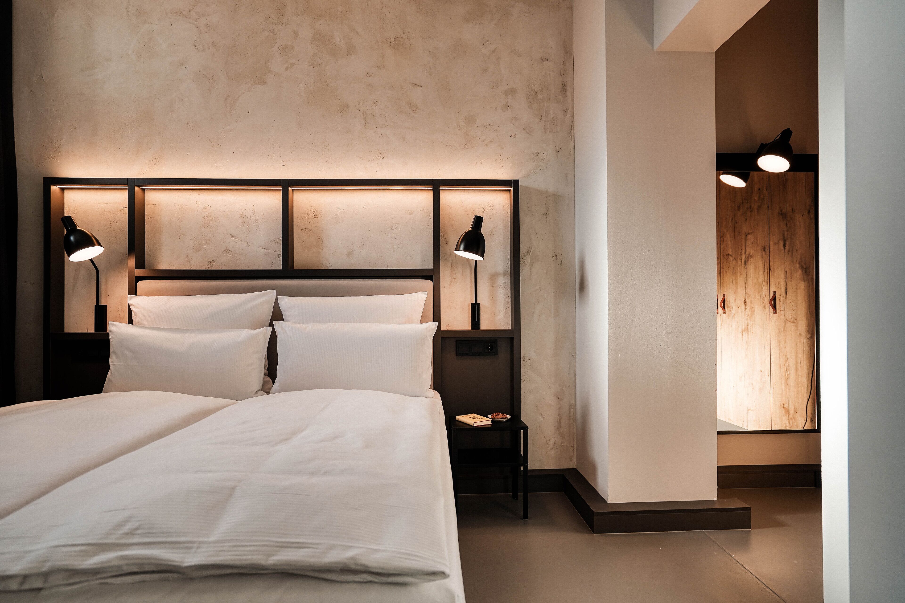 Un dormitorio moderno con una cama grande, dos lámparas de noche y una mesita de noche.