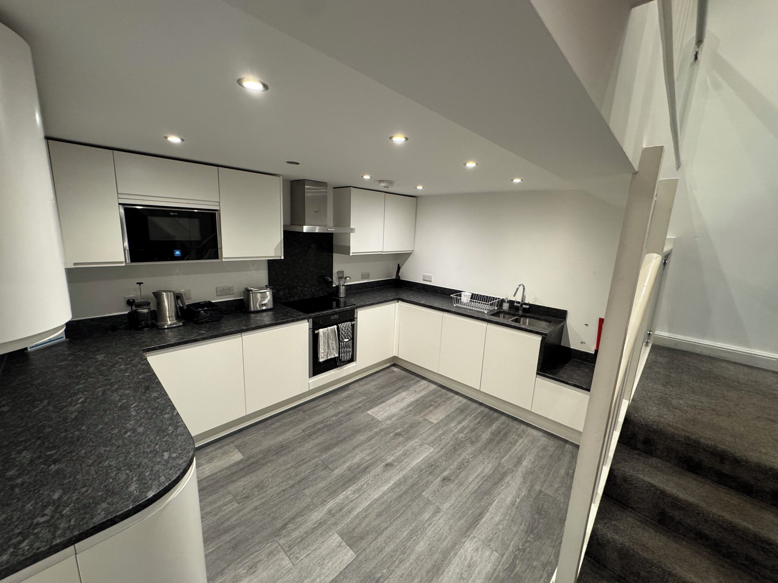 A modern kitchen with white cabinets, a black countertop, and a built-in oven.