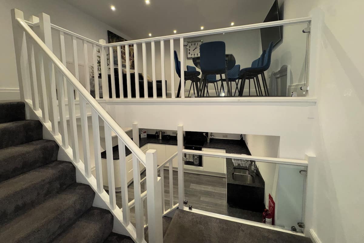 Een trap met witte leuningen die leidt naar een gedeelte op de tweede verdieping, met een eettafel en stoelen.