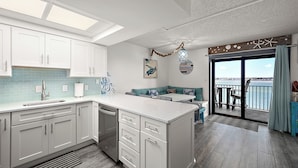 A modern kitchen with white cabinets, a large island, and a view to the outside. - Updated, Direct Bay Front, Bay Front Pool, 3 Blocks to Beach and Boardwalk (Ocean City)