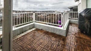 Un balcon doté d’un plancher en bois et de balustrades blanches, donnant sur un quartier résidentiel.