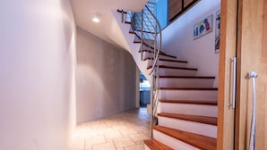 Un intérieur moderne avec un mur incurvé, un escalier en colimaçon et une porte en bois.