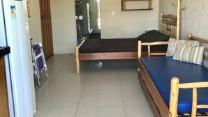 Una habitación con cama, una mesita, un refrigerador y un calentador de pared.