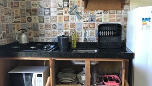 Una cocina con salpicadero de azulejos, microondas, lavabo y refrigerador.