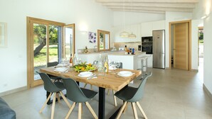 A modern kitchen with a wooden table set for dining, surrounded by chairs. - VILLA MIR - LUXURY RETREAT (Pollensa)