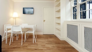 A room with a white table and chairs, a TV mounted on the wall, and a door with a handle. - Victoria Charming Atmosphere (London)