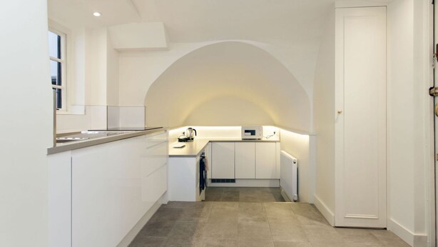 A modern kitchen with white cabinetry, a built-in oven, and a microwave. - Victoria Charming Atmosphere (London)