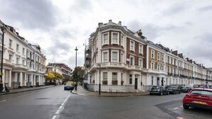 A street lined with terraced houses, a clear road, and parked cars. - Victoria Charming Atmosphere (London)
