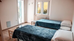 Une petite pièce lumineuse, avec deux lits, une table et une fenêtre.