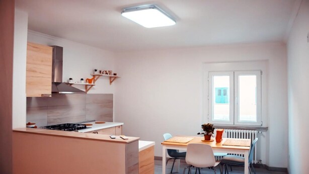 Une cuisine moderne équipée d’une cuisinière à gaz, de meubles en bois et d’une fenêtre avec des stores.