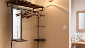 Ein kleines Zimmer mit einem Etagenbett, einem Wäscheständer, einem kleinen Hocker und einem Nachttisch mit Lampe.