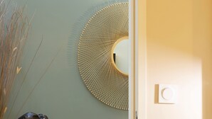 Ein Zimmer mit Schreibtisch aus Holz, einem gewebten Korb, einem Wandspiegel und einer Statue.