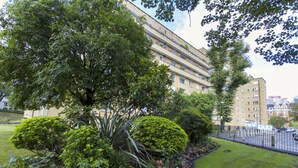 Um edifício residencial de vários andares com um jardim bem cuidado na frente.