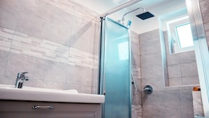 A modern bathroom with a glass shower enclosure, a sink with a faucet, and a tiled floor. - Apartment two bedrooms two bathrooms (Ancona)