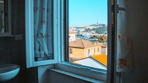 Un baño con ventana que da a una vista urbana.