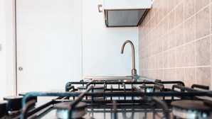 Una cocina con estufa a gas, un fregadero y un salpicadero de azulejos.