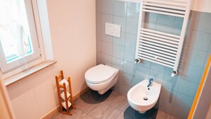Un baño pequeño con inodoro, bidé y ventana.