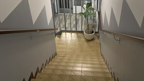 A staircase with patterned walls and a potted plant at the bottom. - Hotel bon accueil (Oyonnax)