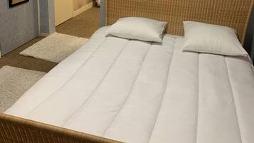Un dormitorio con una cama grande, un cabecero de mimbre y una puerta que da al baño.