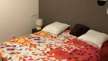 Ein Schlafzimmer mit Bett, Kissen, einem Nachttisch, einer Lampe und Wanddekorationen.