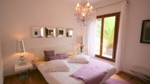 Una camera da letto con un letto grande, un lampadario, un comodino e una finestra con tende.