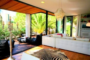 A modern living room with a white sofa, a zebra-patterned rug, and a chandelier.