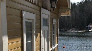 A wooden house with a porch, a lantern, and a view of a lake.