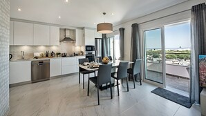 A modern kitchen with a dining area and large sliding glass doors leading to a balcony with a city view. - Luxurious Apartment with Private Terrace & Jacuzzi (Tavira)