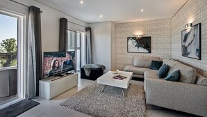 A modern living room with a flat-screen TV, a sofa, a coffee table, and a patterned rug. - Luxurious Apartment with Private Terrace & Jacuzzi (Tavira)