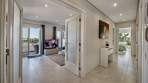 A modern interior with a living area, a TV, a painting, and a balcony with a view. - Luxurious Apartment with Private Terrace & Jacuzzi (Tavira)