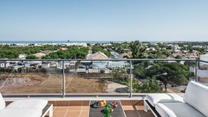 A balcony with a clear view of a coastal town, a dining table with fruits, and white lounge chairs. - Luxurious Apartment with Private Terrace & Jacuzzi (Tavira)