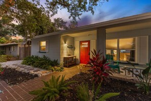 A modern house with a red door, a covered porch, and a garden with various plants. - Siesta Key vacation rental home close to village with swimming pool and free wifi (Siesta Key)
