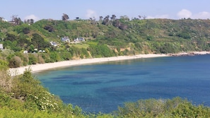 A coastal landscape with a sandy beach, clear blue waters, and a hillside with scattered houses. - Vacation Home on the Pink Granite Coast (Trébeurden)