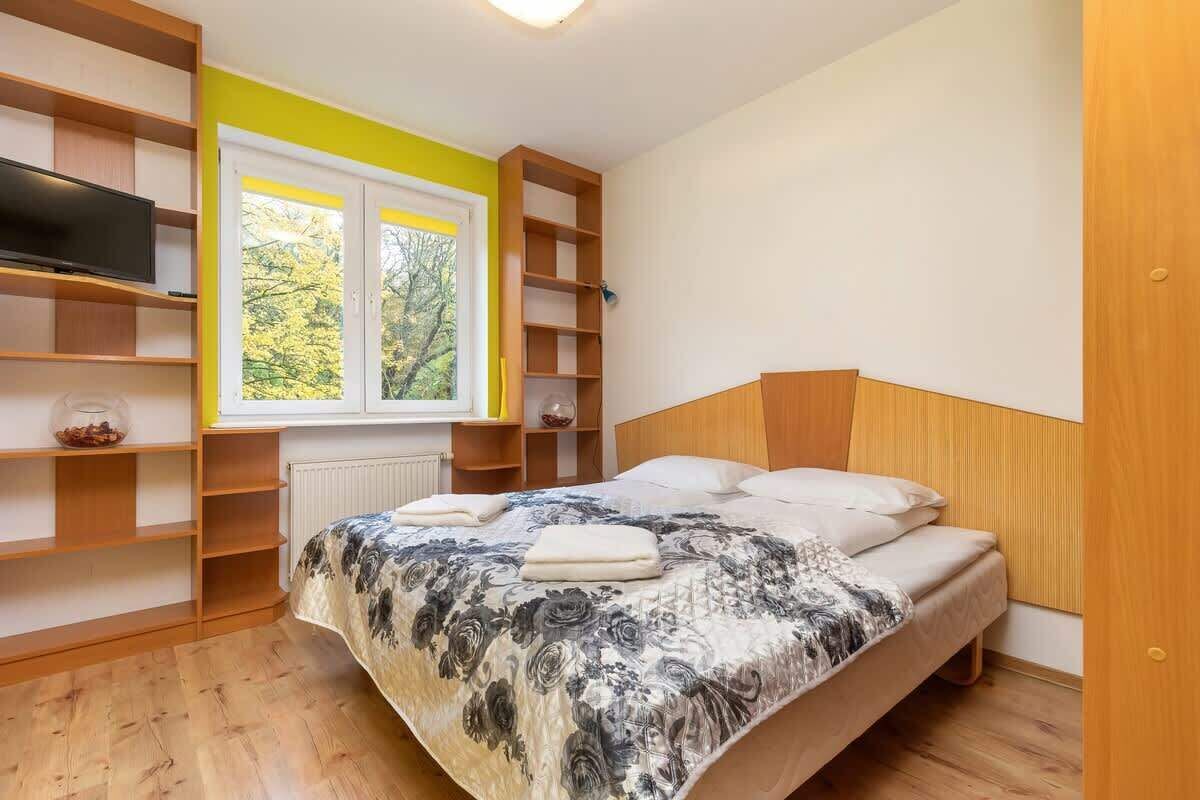 Ein Schlafzimmer mit einem Bett, einem Fernseher und einem Fenster mit Blick auf Bäume.
