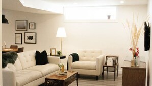 A modern living room with a sofa, armchairs, a coffee table, and a lamp. - Walk to Hospital - Medical Workers Suite (Lethbridge)
