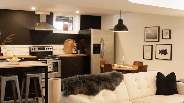 A modern kitchen with a dining area, featuring a sofa and a table with chairs. - Walk to Hospital - Medical Workers Suite (Lethbridge)